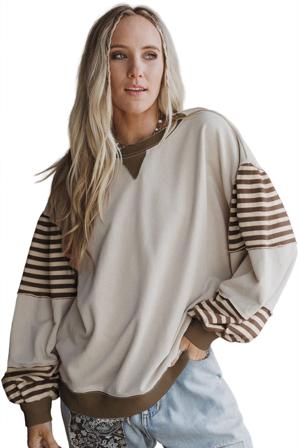 Woman wearing a beige sweater with striped sleeves on a white background