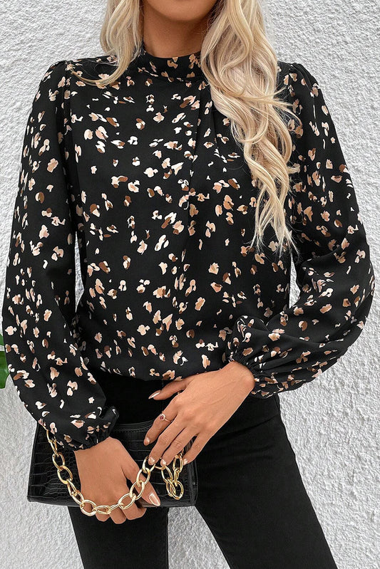 Woman wearing a black floral blouse against a white wall
