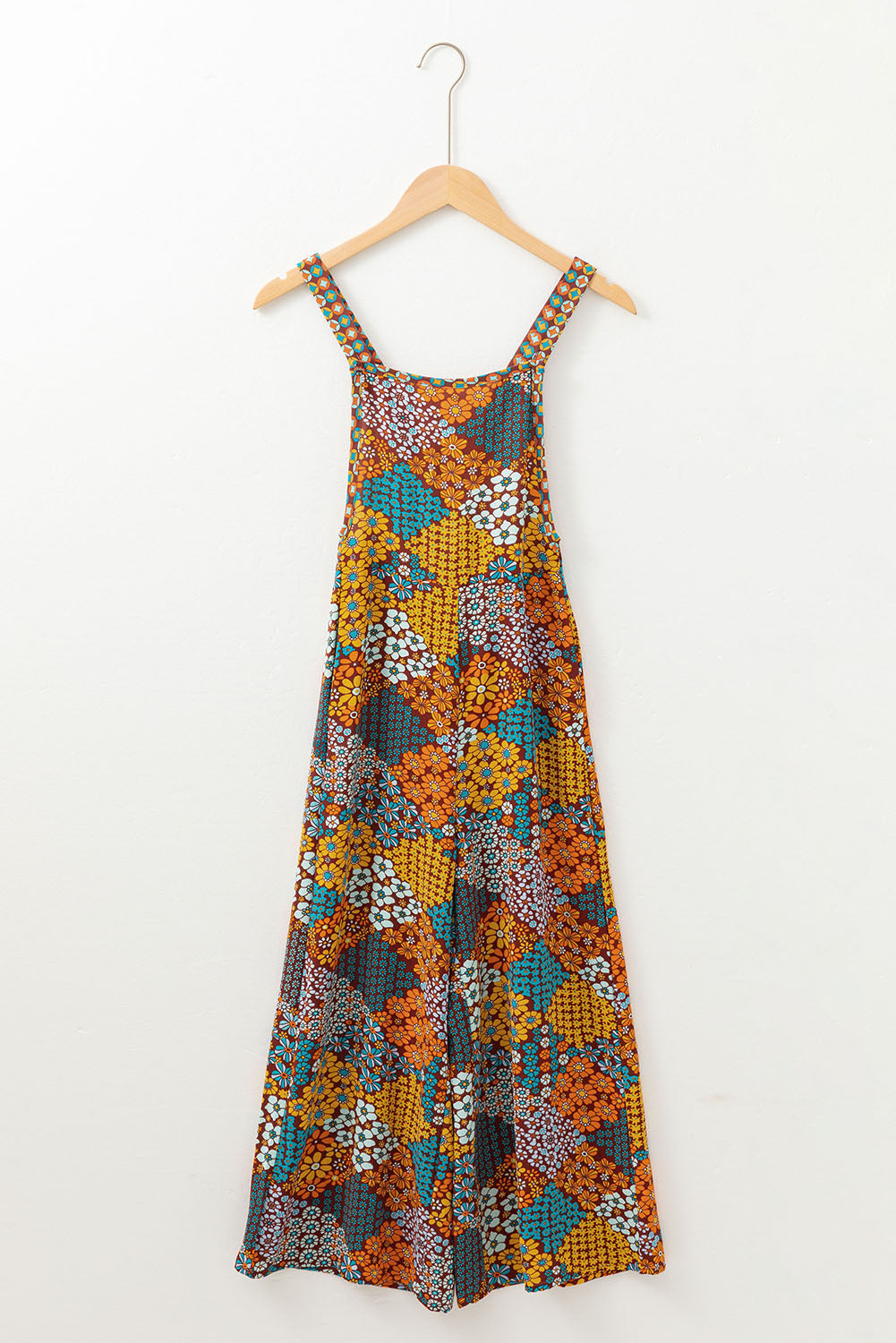 Colorful floral dress on a hanger against a white background