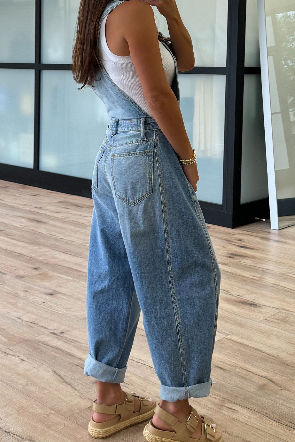 Person wearing a denim jumpsuit standing on a wooden floor.