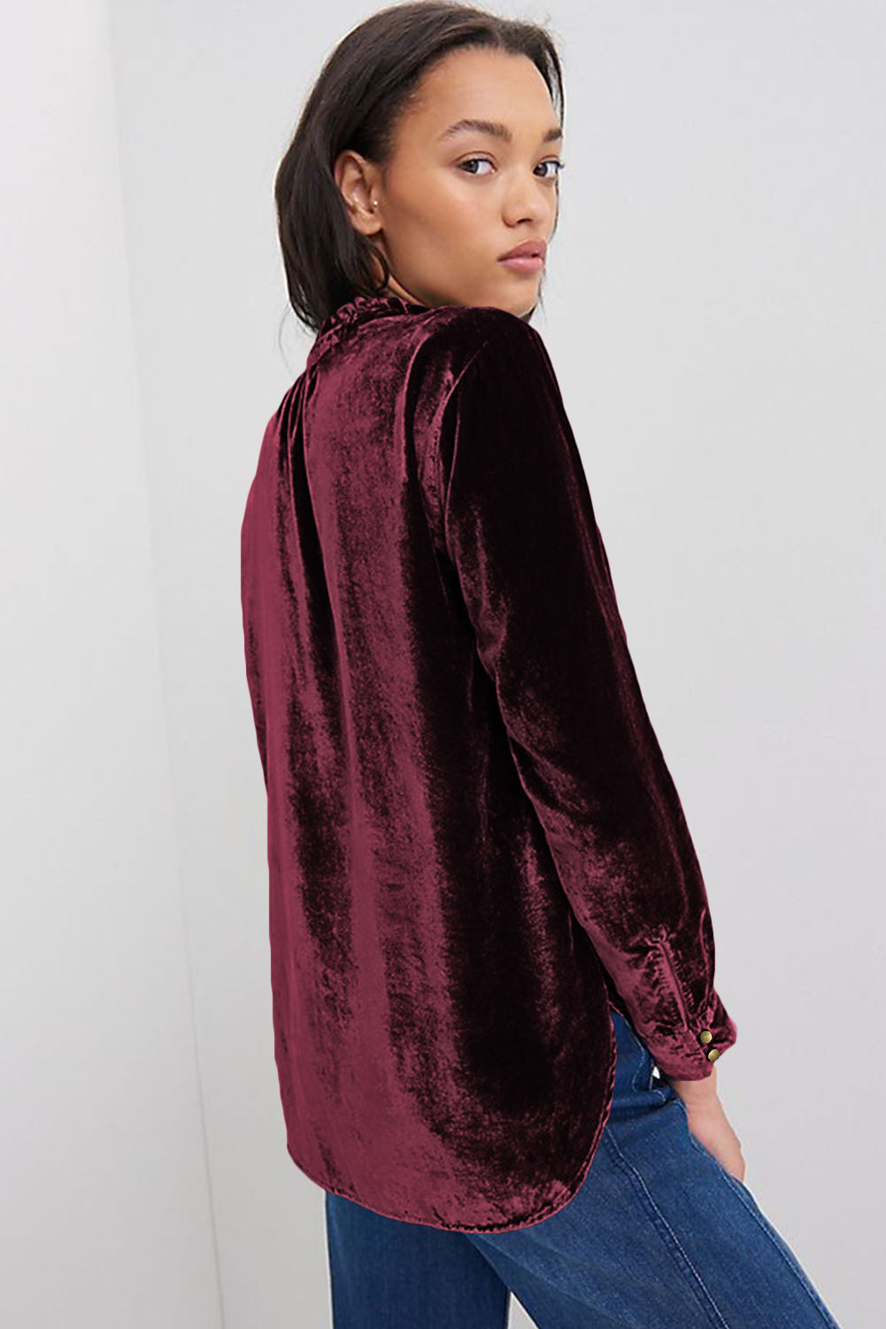 Woman wearing a burgundy velvet shirt against a white background