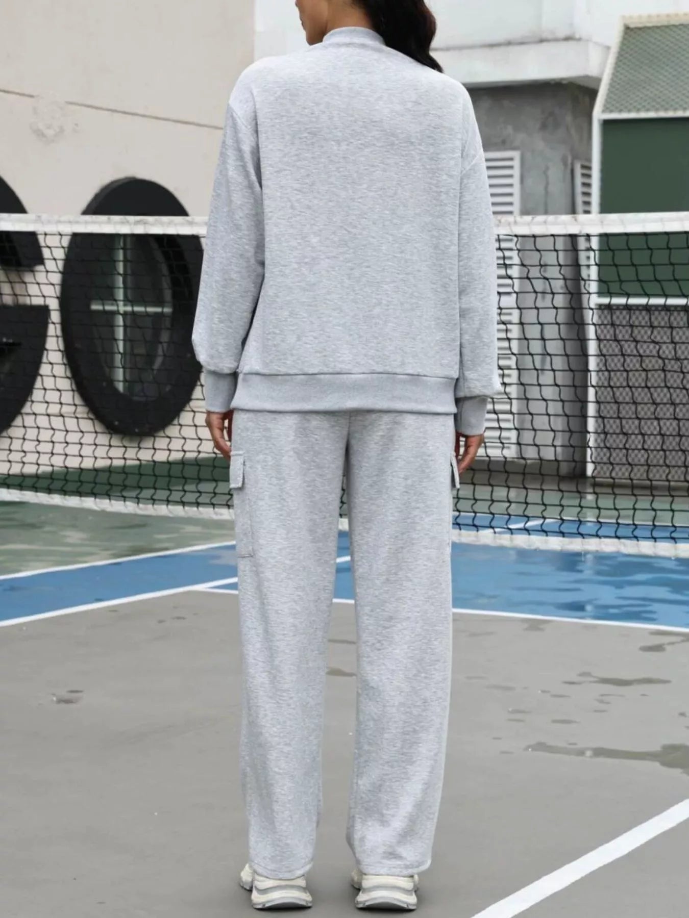 Person wearing a gray tracksuit on an outdoor court