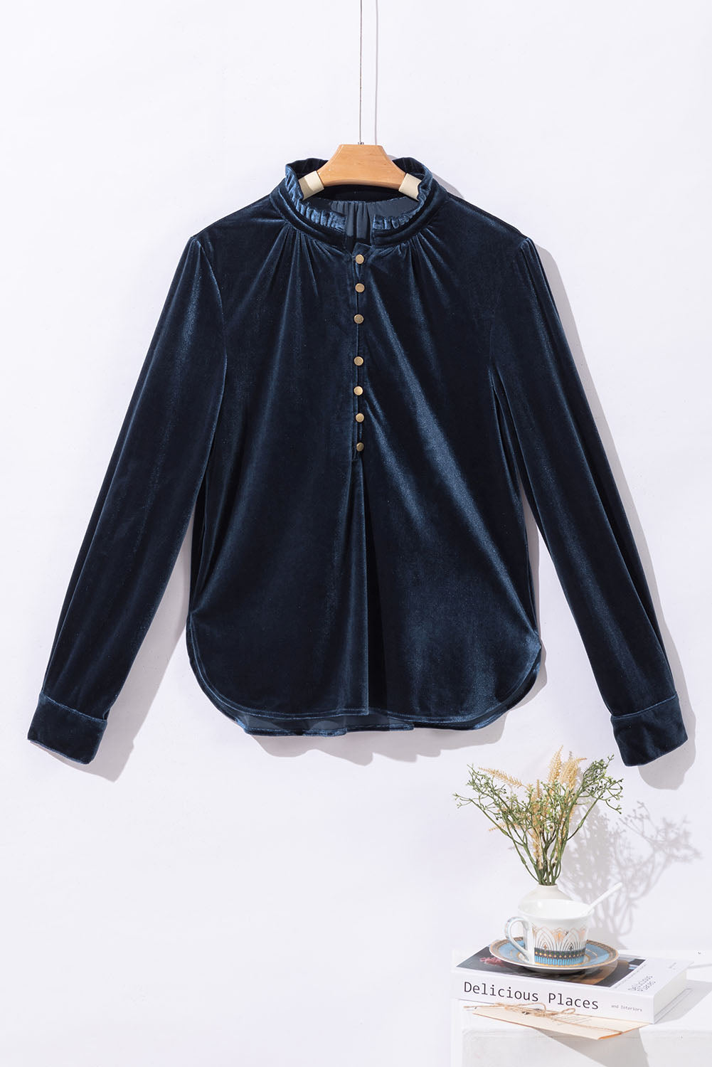 Navy velvet blouse on a hanger with a white background