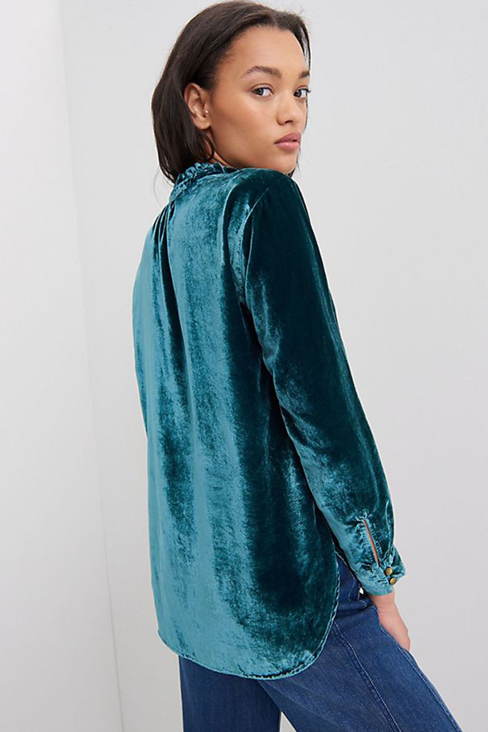 Woman wearing a teal velvet shirt against a white background