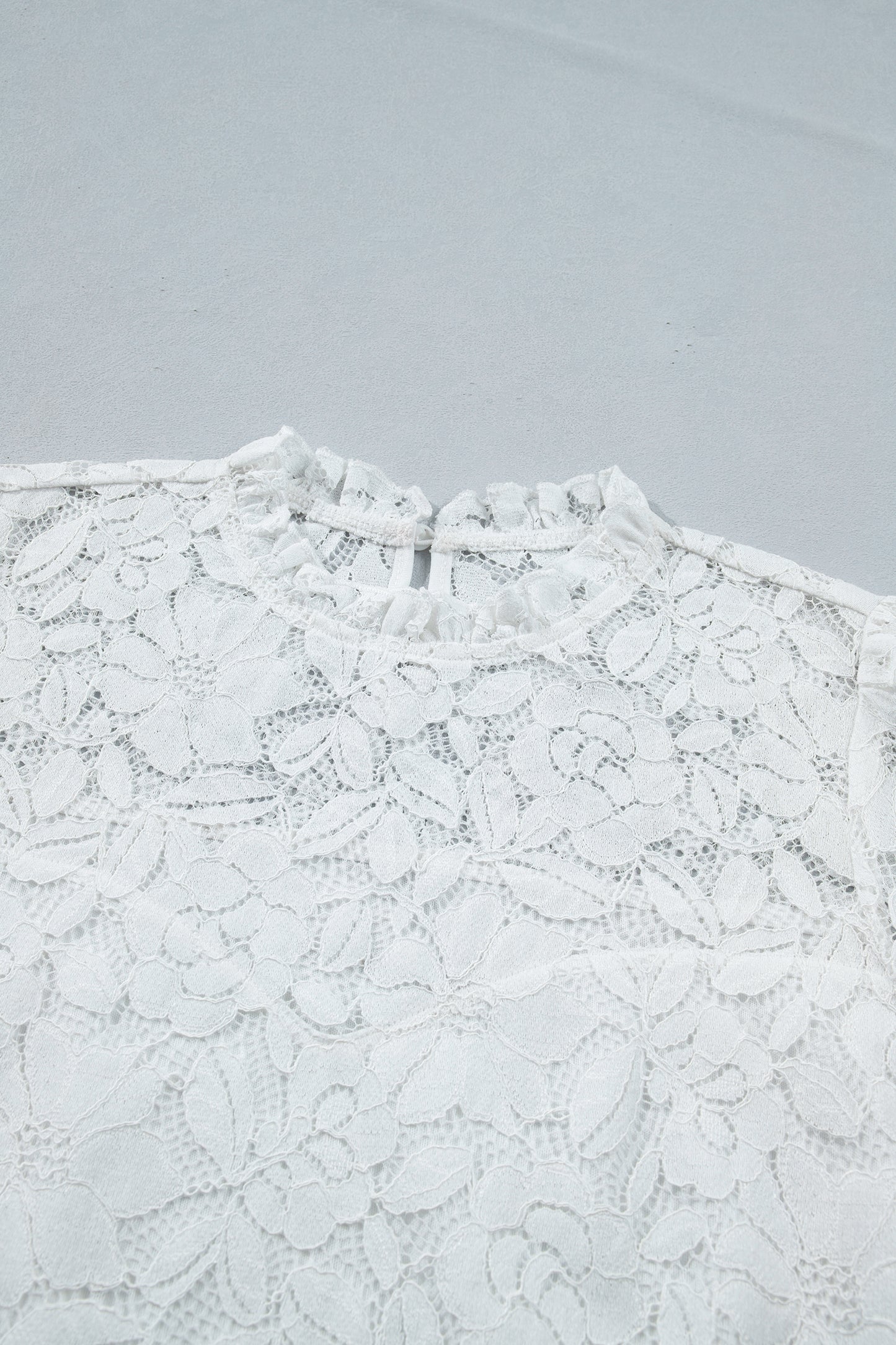 White lace top on a light gray background detailed view