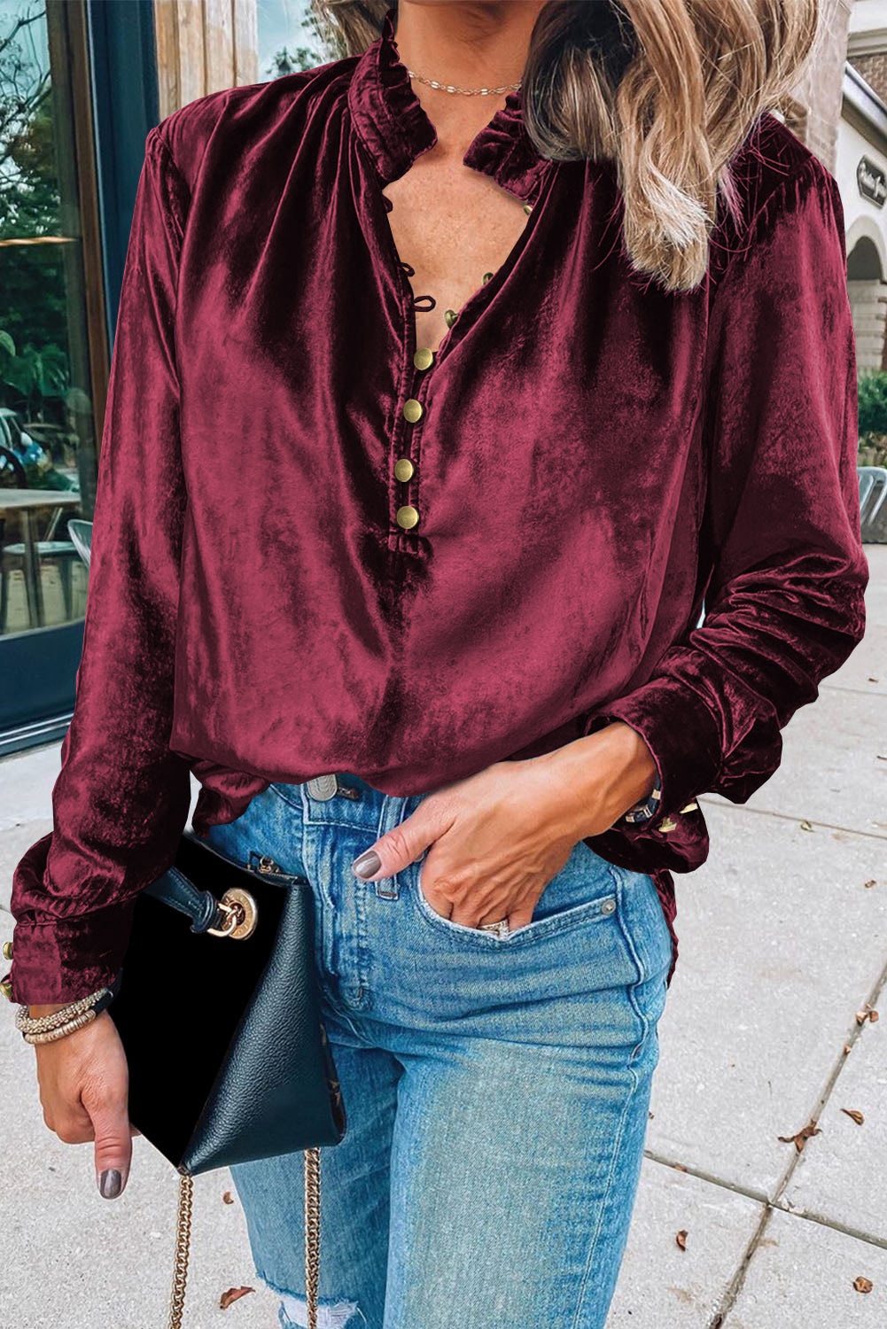 Person wearing a burgundy velvet shirt and blue jeans outdoors.