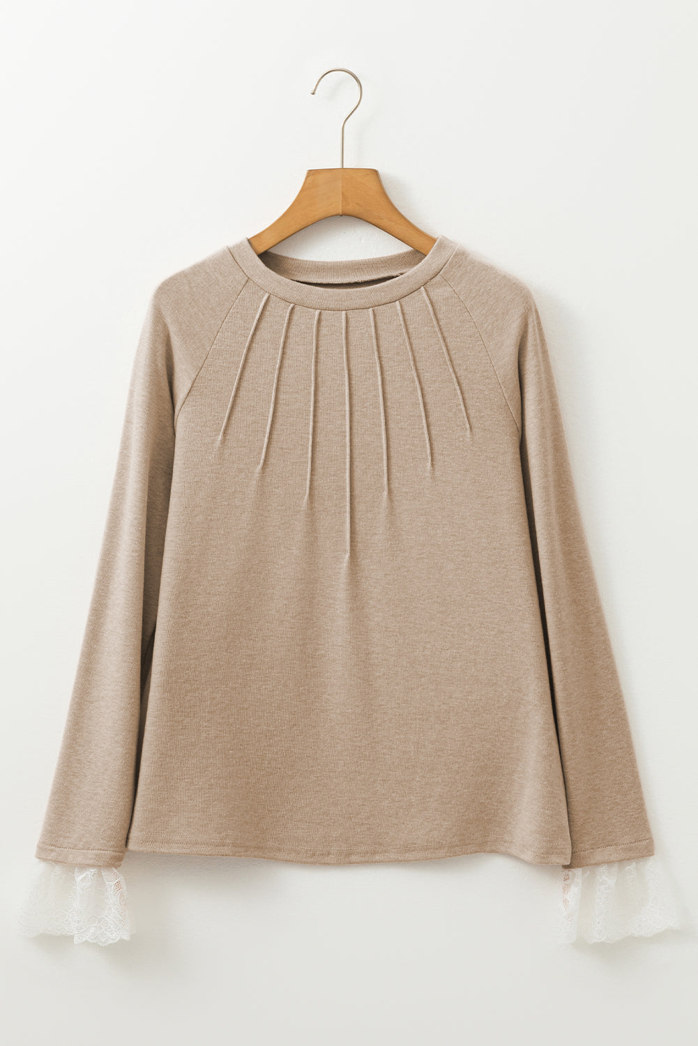Beige long-sleeve top on a wooden hanger against a white background