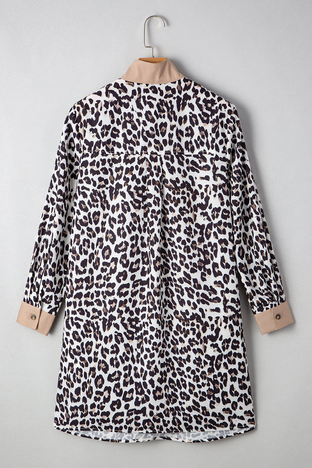 Back view of a leopard print dress hanging on a wooden hanger, featuring a collar and button-down design