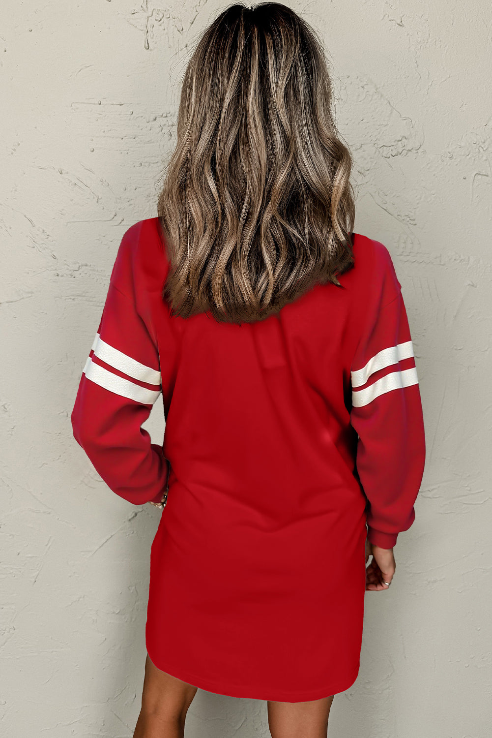 Back view of a model in an red colorblock athletic dress showcasing long sleeves and sporty stripes
