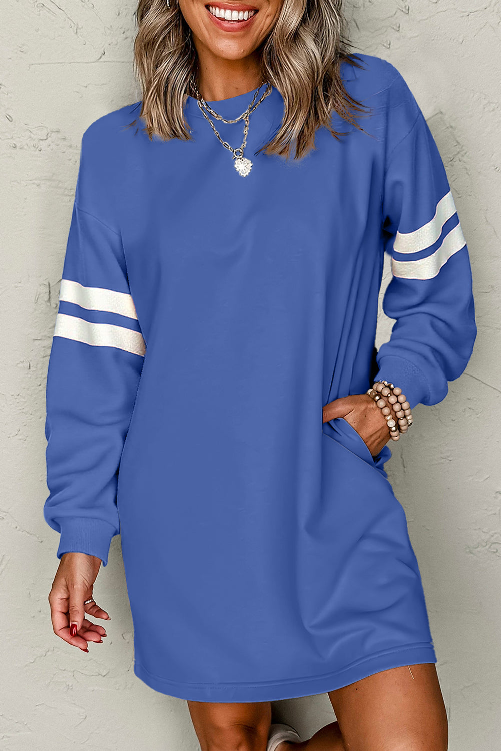Close-up of a model in an blue athletic dress, featuring side pockets and sporty white stripes