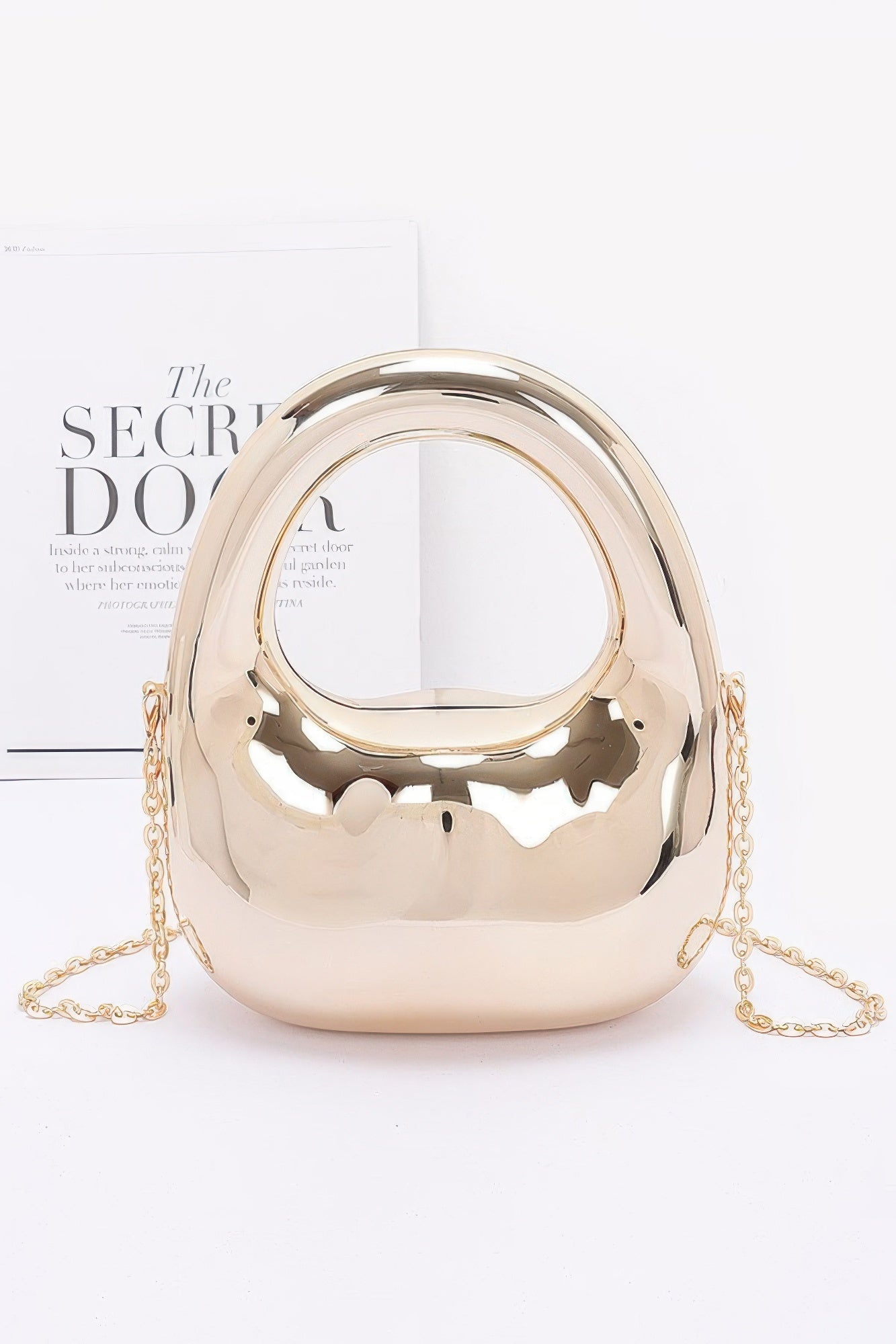 Gold metallic handbag with chain strap on a white background