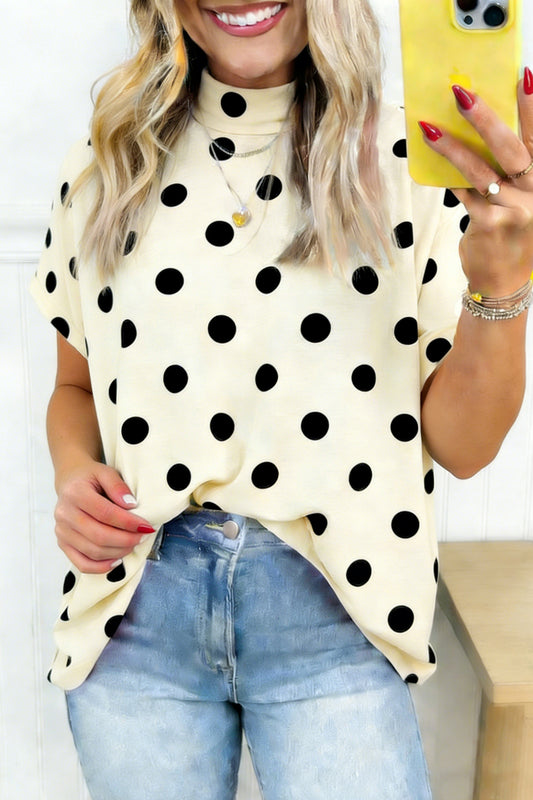 Woman wearing a polka dot top and jeans, holding a yellow phone.
