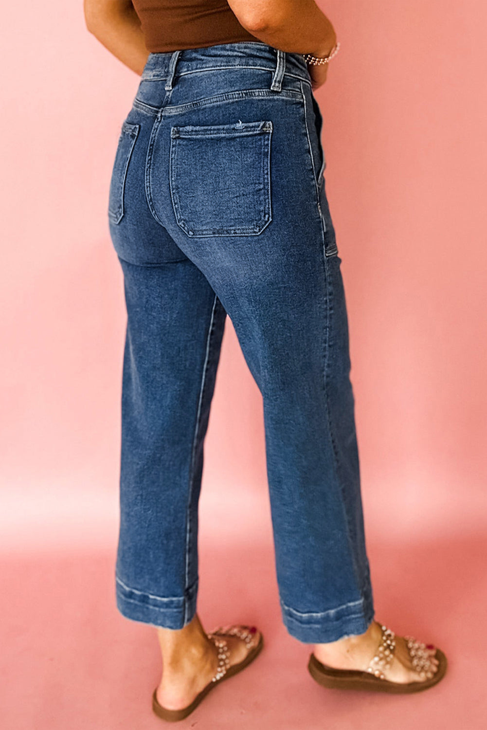 Person wearing blue jeans on a pink background