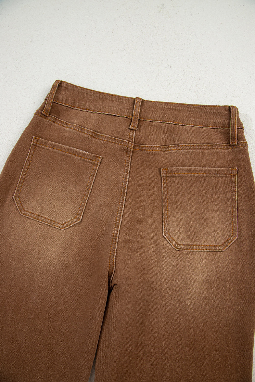 Brown pants with back pocket detail on a light gray background