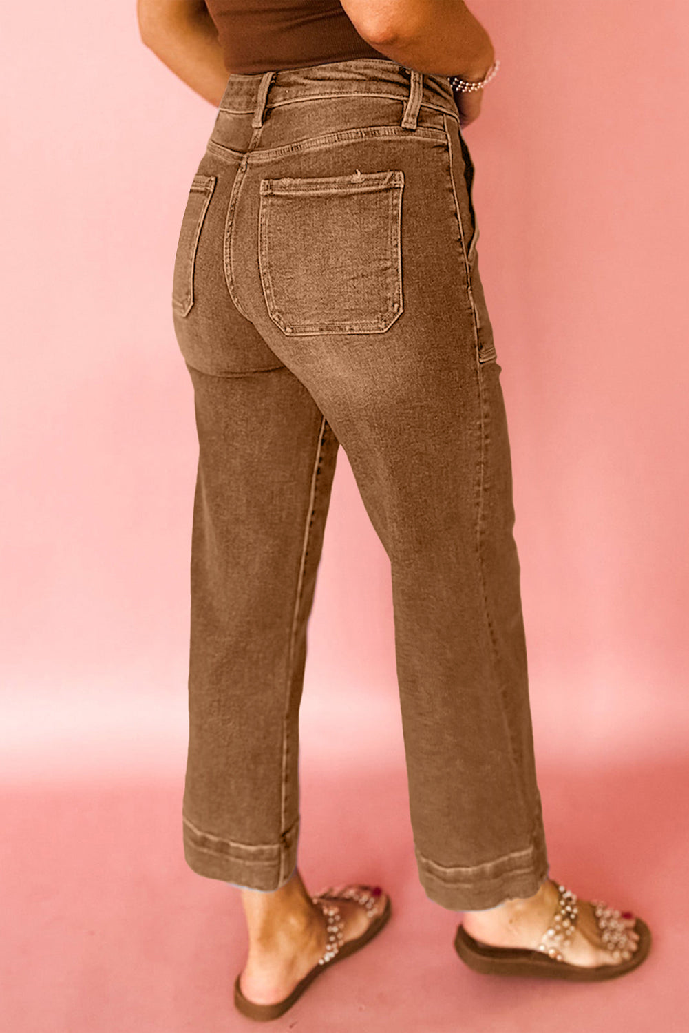 Brown jeans worn by a person on a pink background