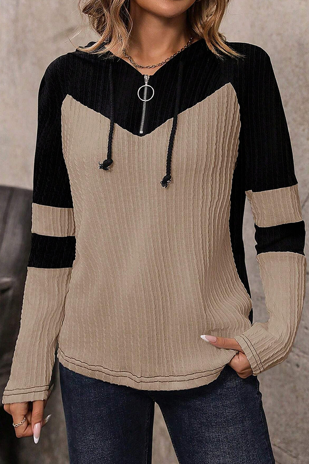 Person wearing a black and beige long-sleeve top with ribbed texture.
