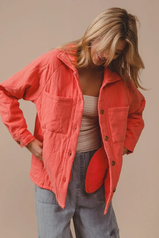 Woman wearing a coral jacket with a neutral background