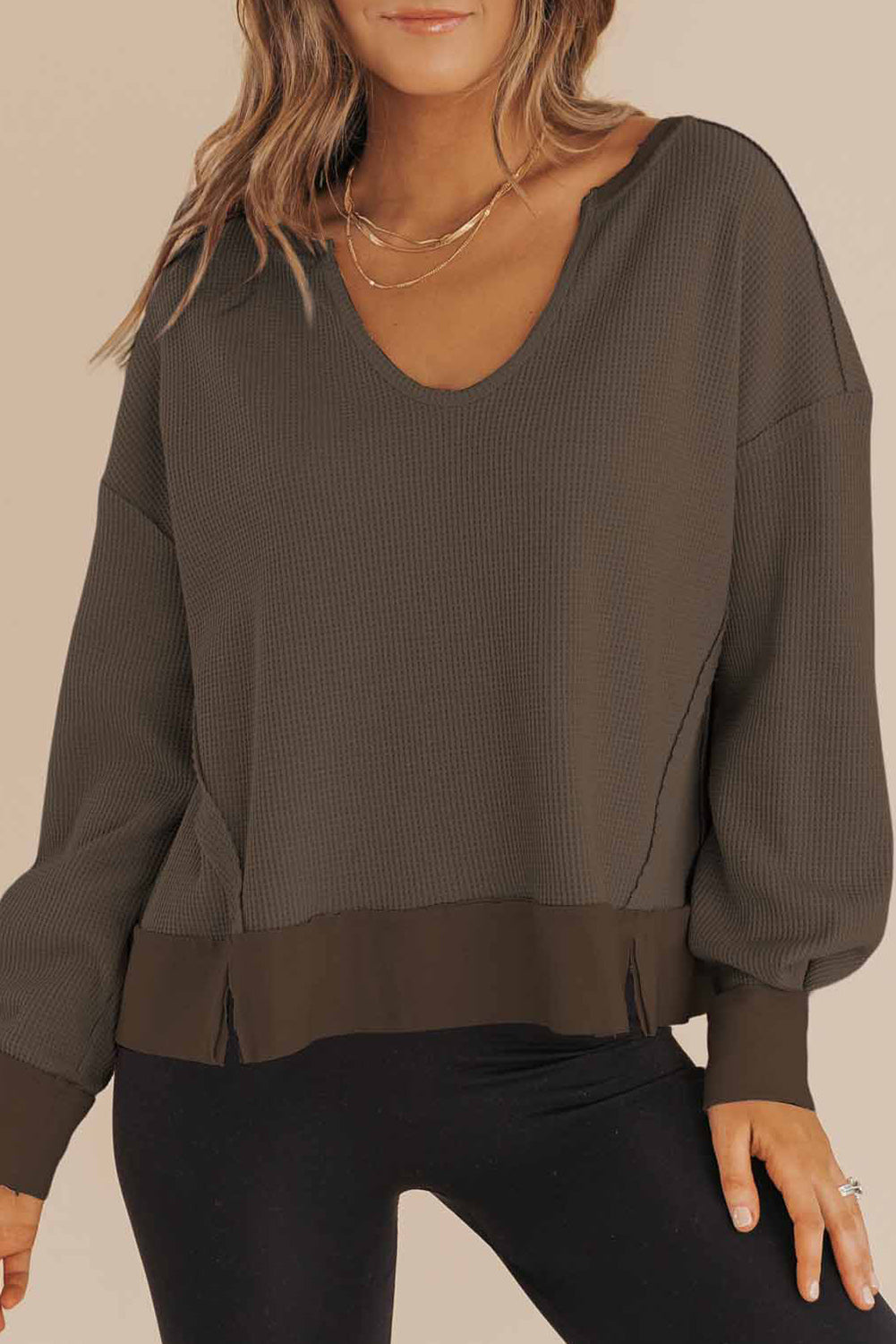 Dark brown sweater worn by a person on a beige background