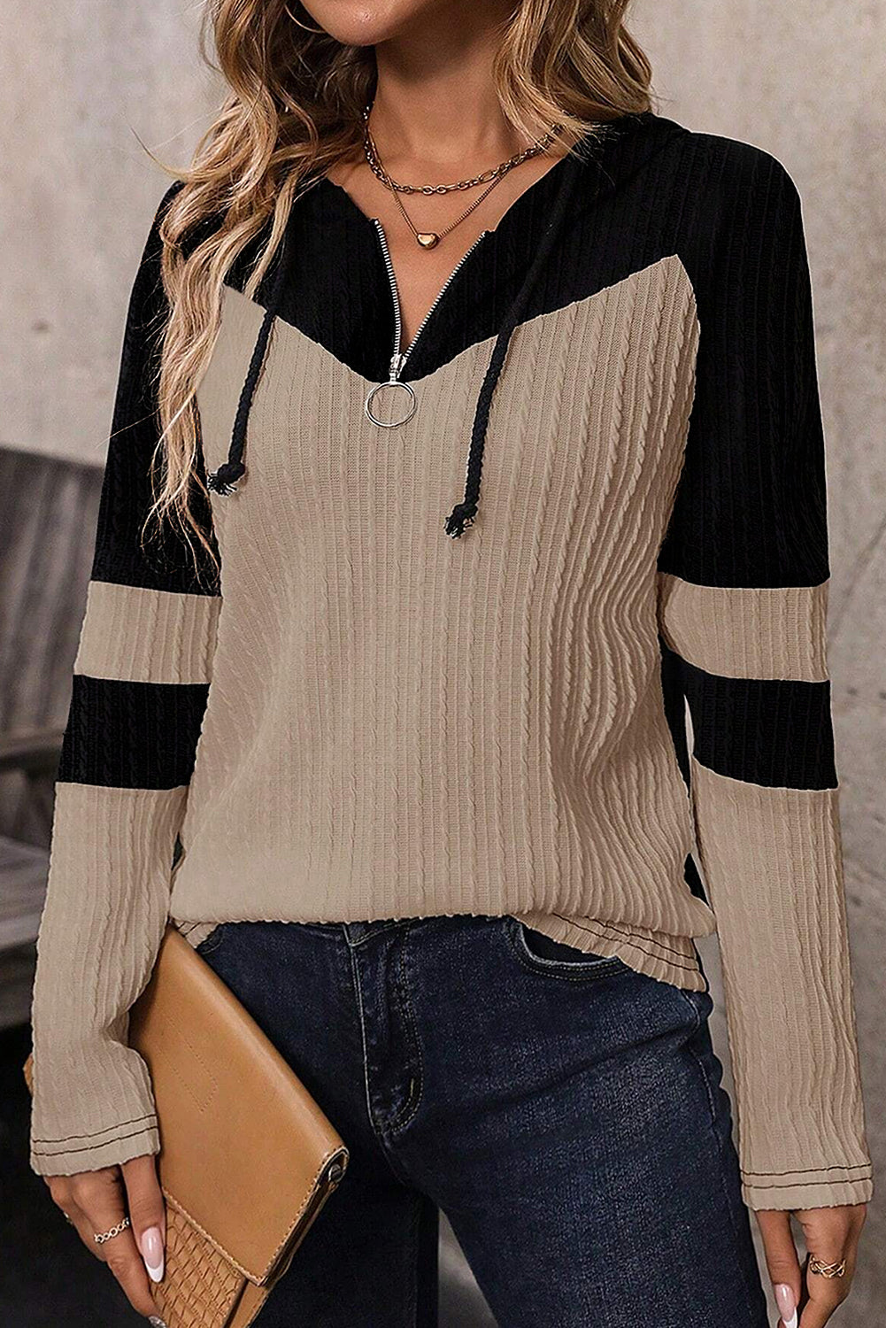 Person wearing a black and beige sweater with a blurred background