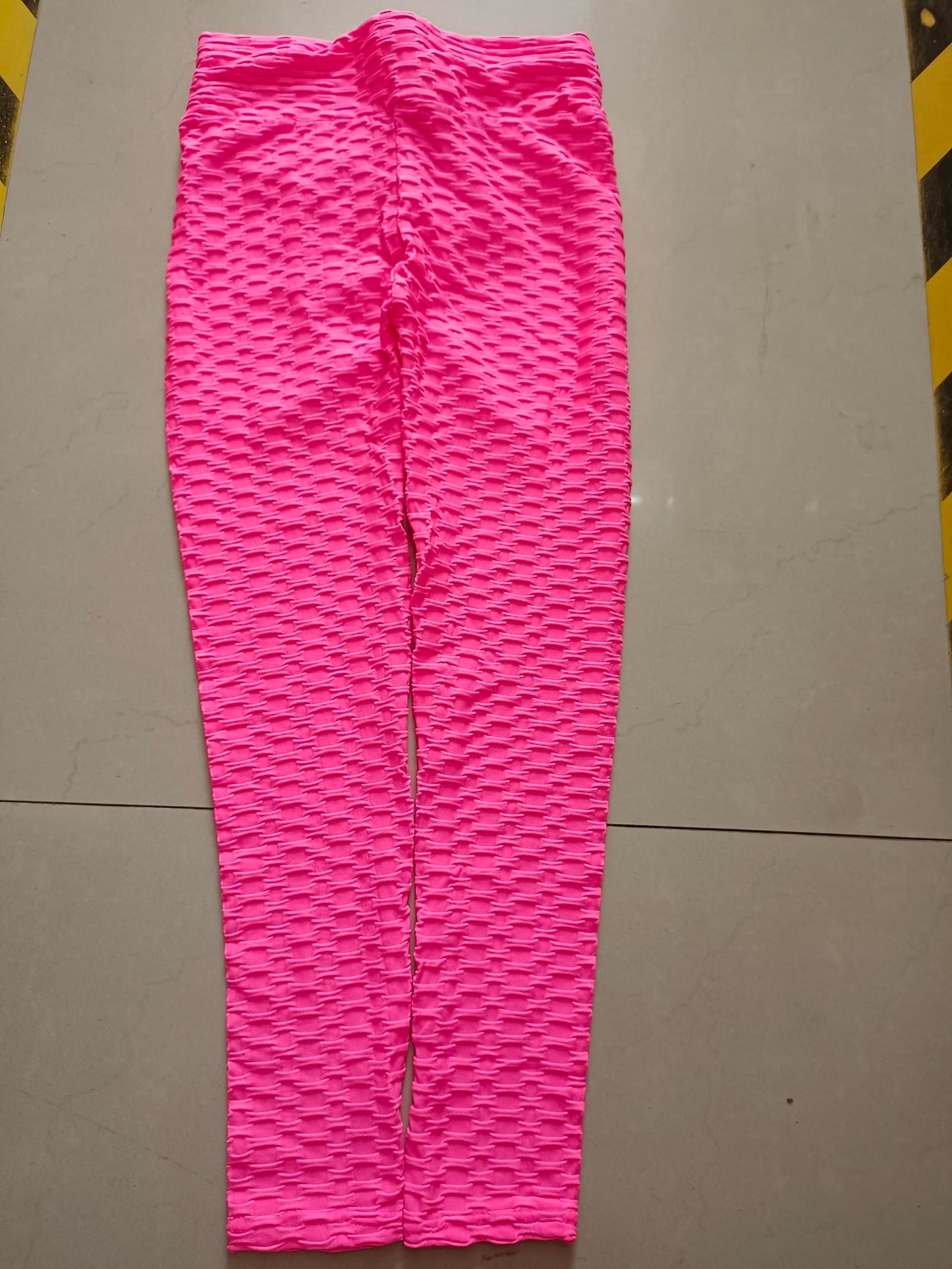 Pink leggings with a wavy pattern on a gray floor.