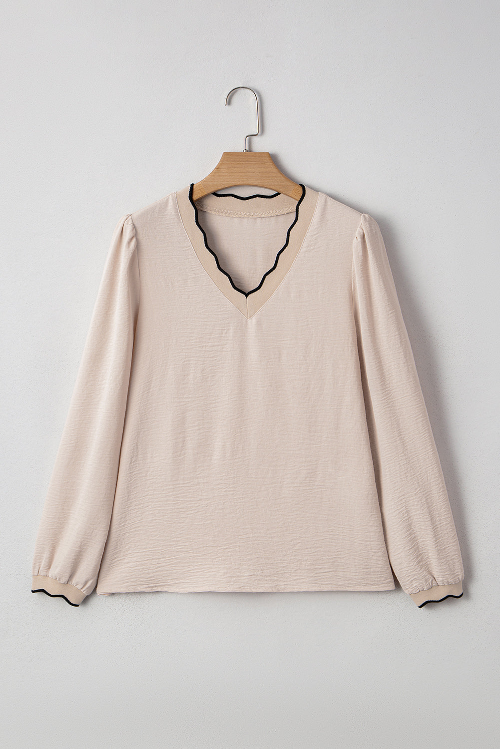 Beige long-sleeve shirt on a wooden hanger against a light gray background