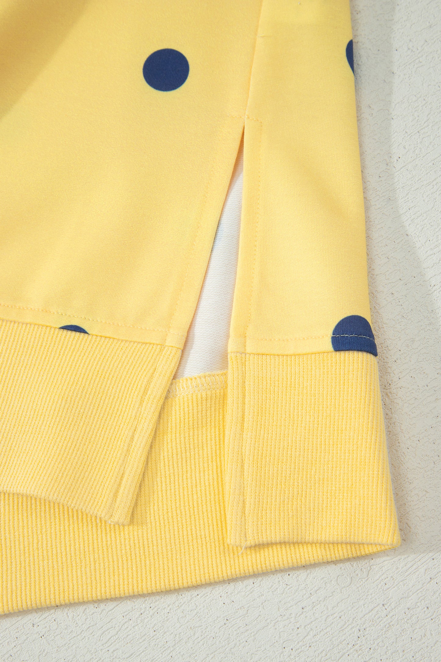 Yellow fabric with blue polka dots on a light gray background detailed view