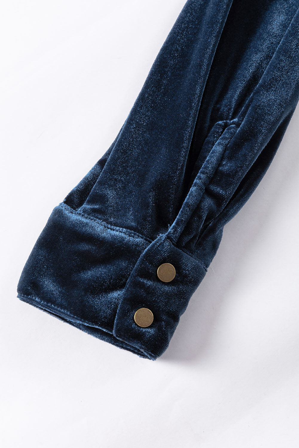 Close-up of a blue velvet garment with buttons on a white background