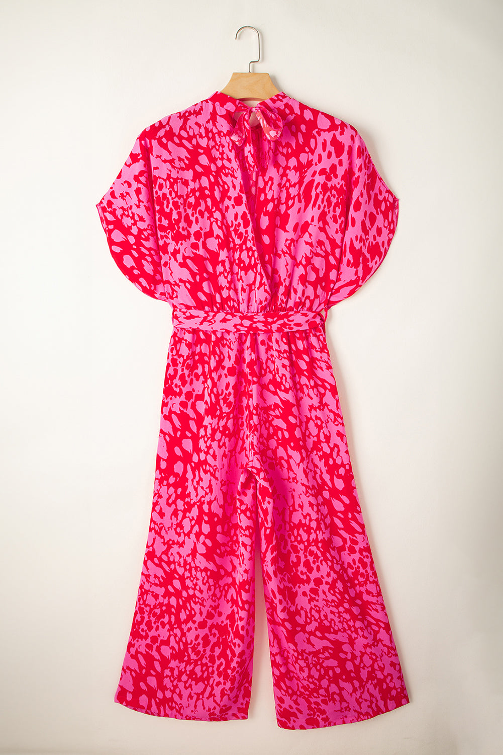 Pink patterned jumpsuit front on a hanger against a white background