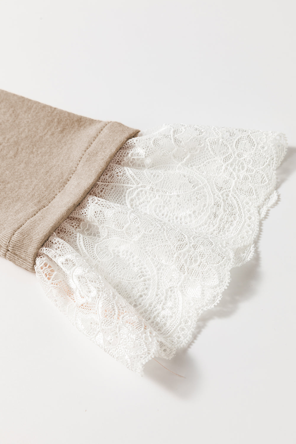 Close-up of beige pants with white lace trim on a light background
