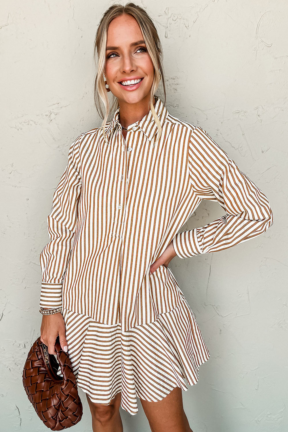 Smiling model wearing a brown and white striped dress with a collar and button-down front, showcasing a flared skirt