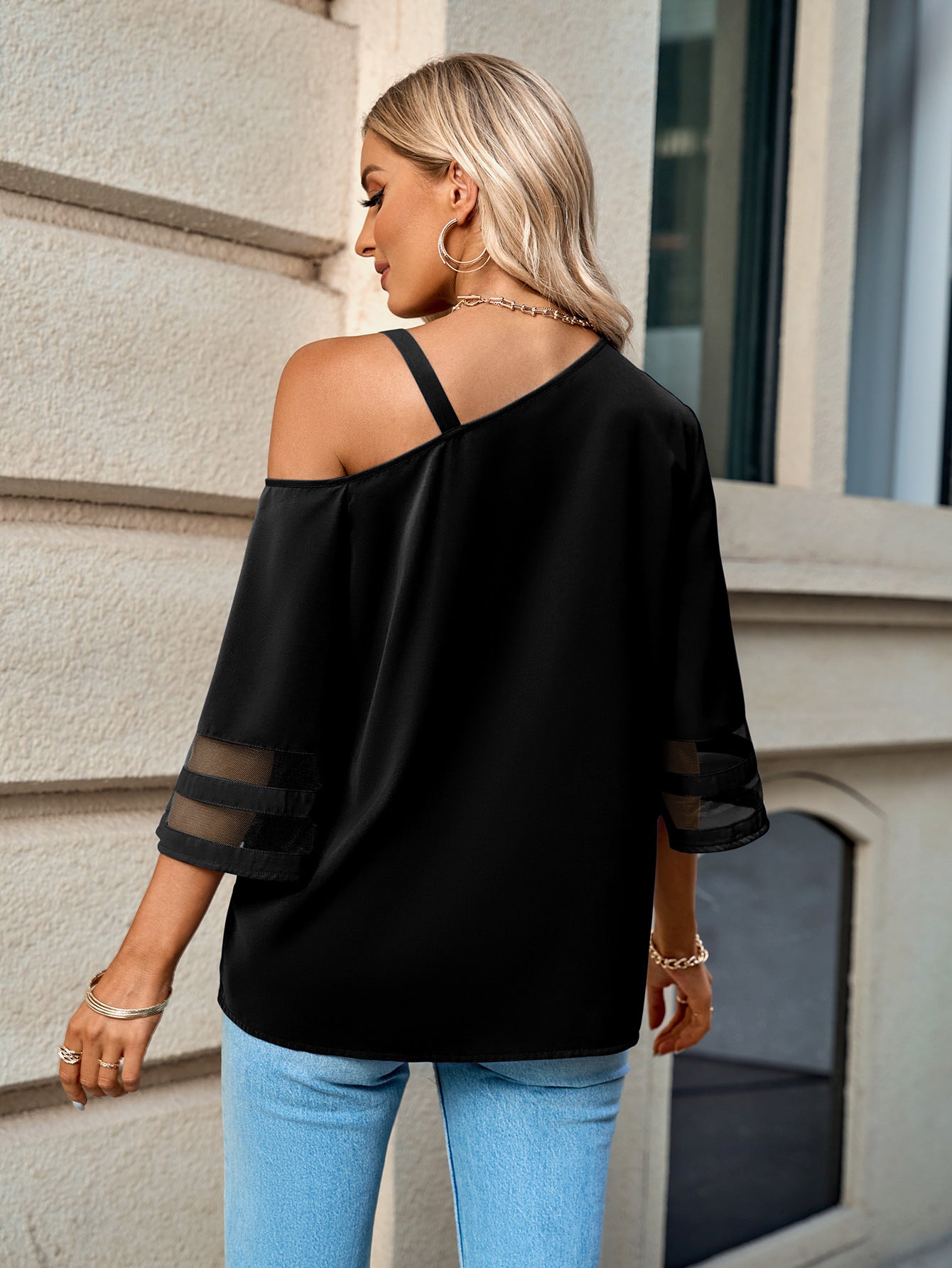 Back view of a model Wearing a Black Ladies Asymmetrical Neck Sheer Striped Flare Sleeve Blouse
