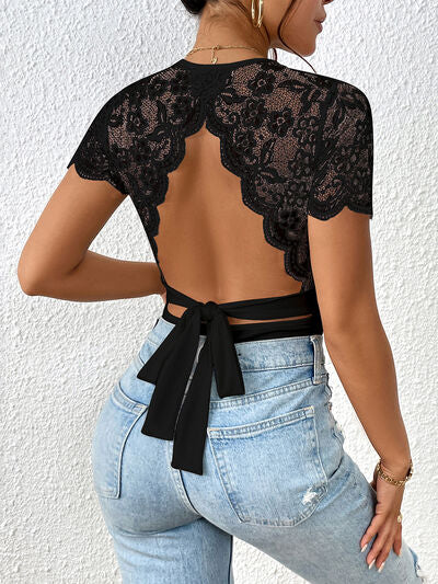 Back view of a Model wearing a Black Flattering Ladies Lace Backless Round Neck Bodysuit with jeans