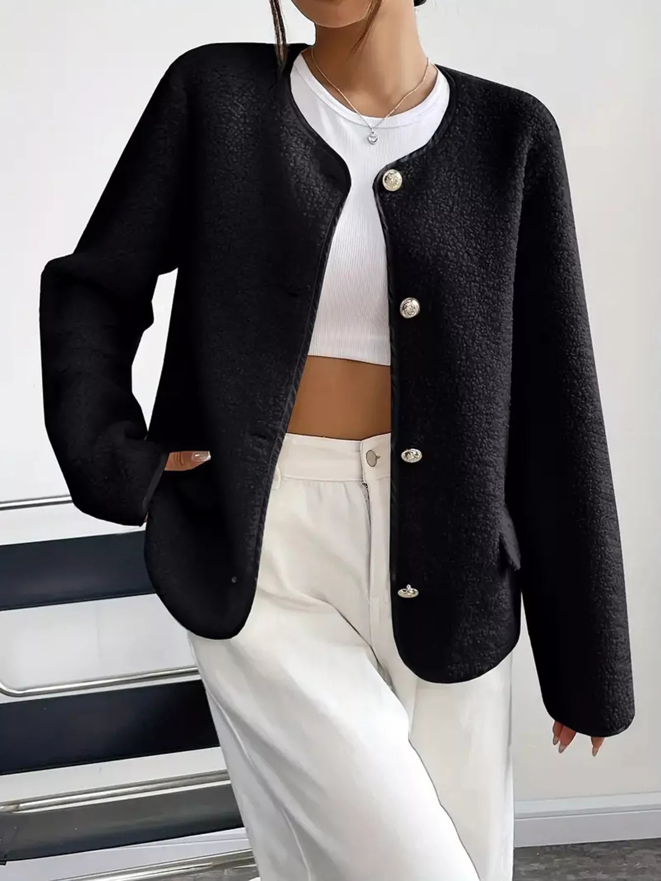 Person wearing a black blazer over a white top and pants on a white background