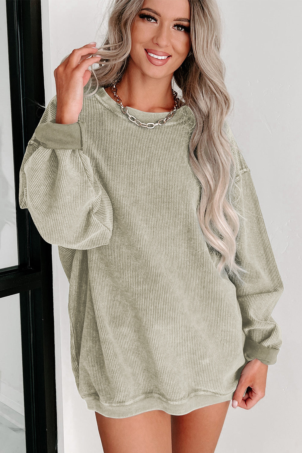 Woman wearing a green ribbed sweater dress against a white background