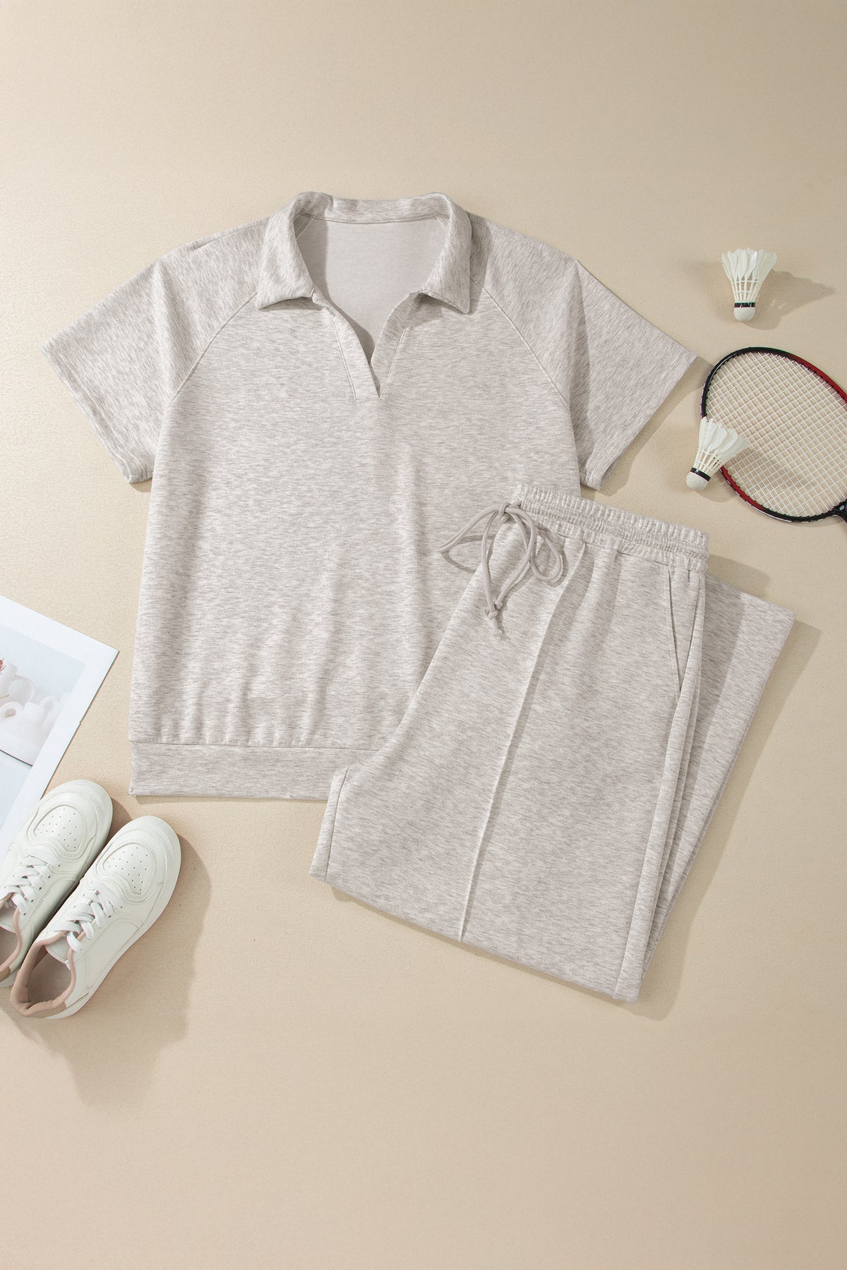 Gray athletic outfit with sneakers and badminton equipment on a beige background