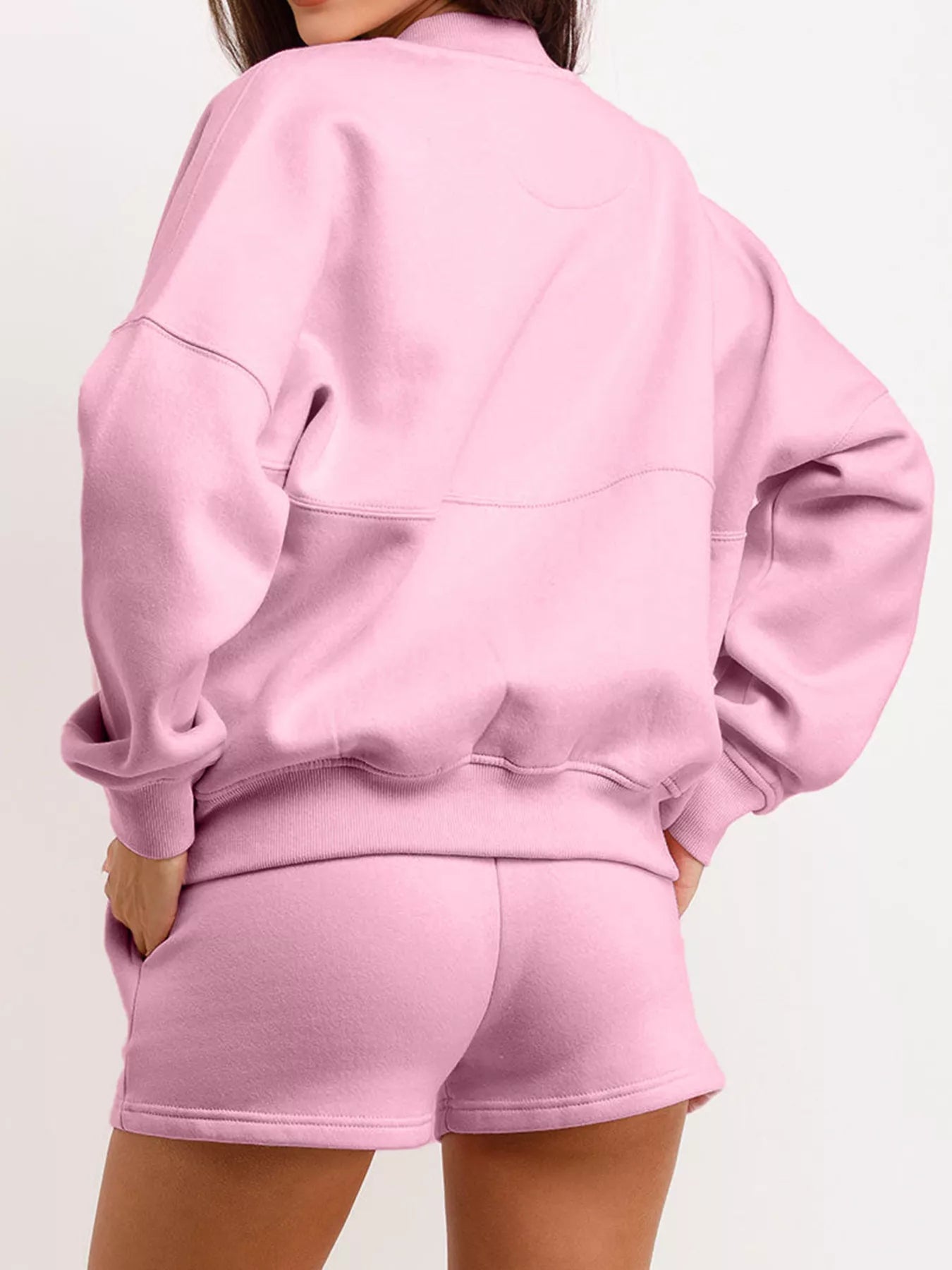 Person wearing a pink sweatshirt and shorts set on a white background