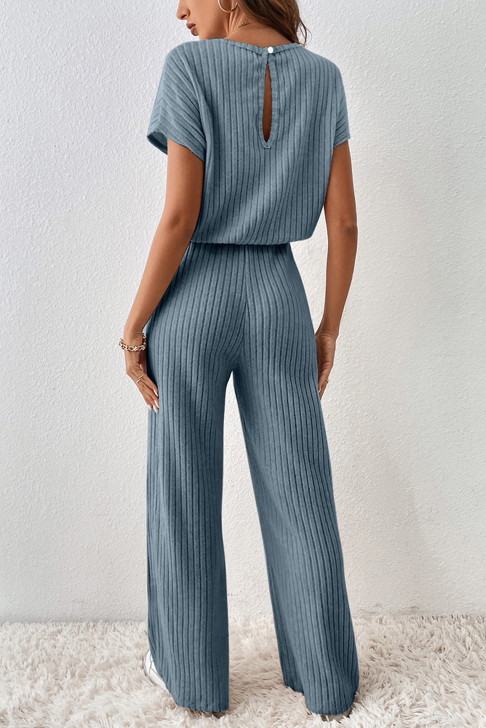 Woman wearing a blue ribbed jumpsuit against a white background