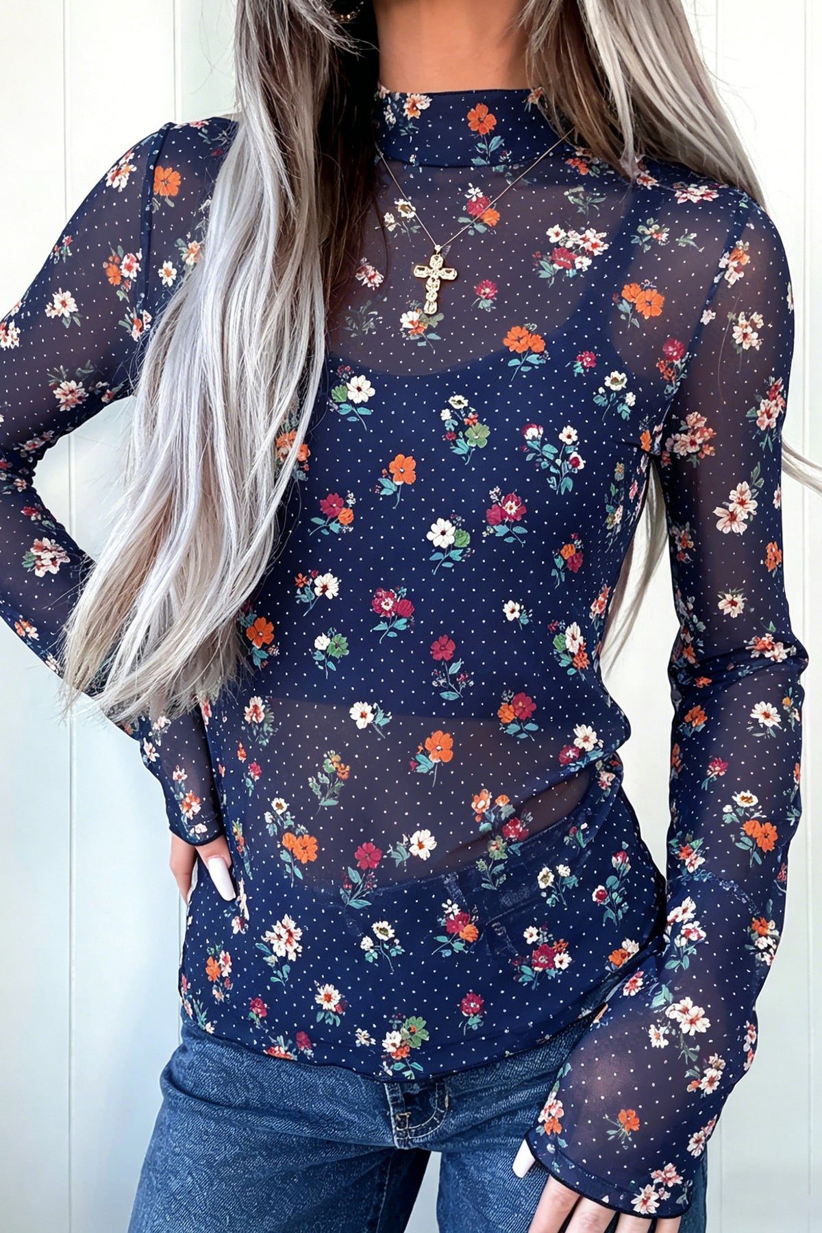 A woman wearing a Chic Women's Blue Polka Dot Floral Sheath Top with a navy blue base and a colorful floral print, paired with blue jeans.