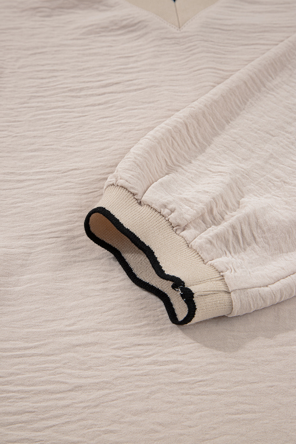 Close-up of a textured white fabric with a black and brown detail on a light beige background