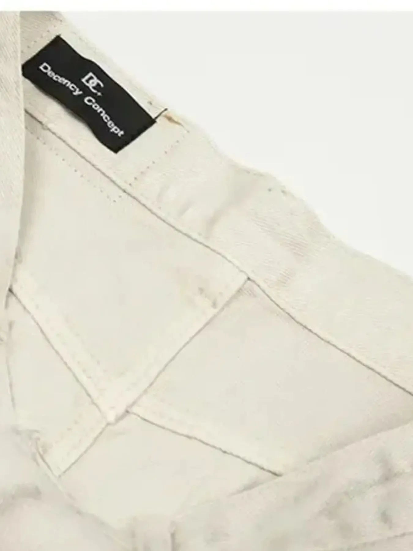 Close-up of a pair of vintage washed off white jeans with a brand label 