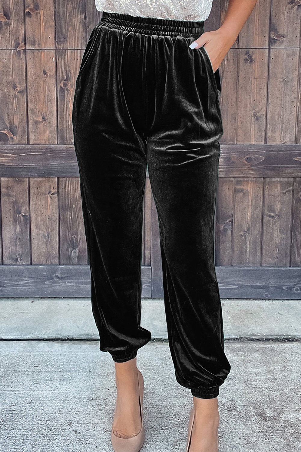 Black velvet pants worn by a person against a wooden background