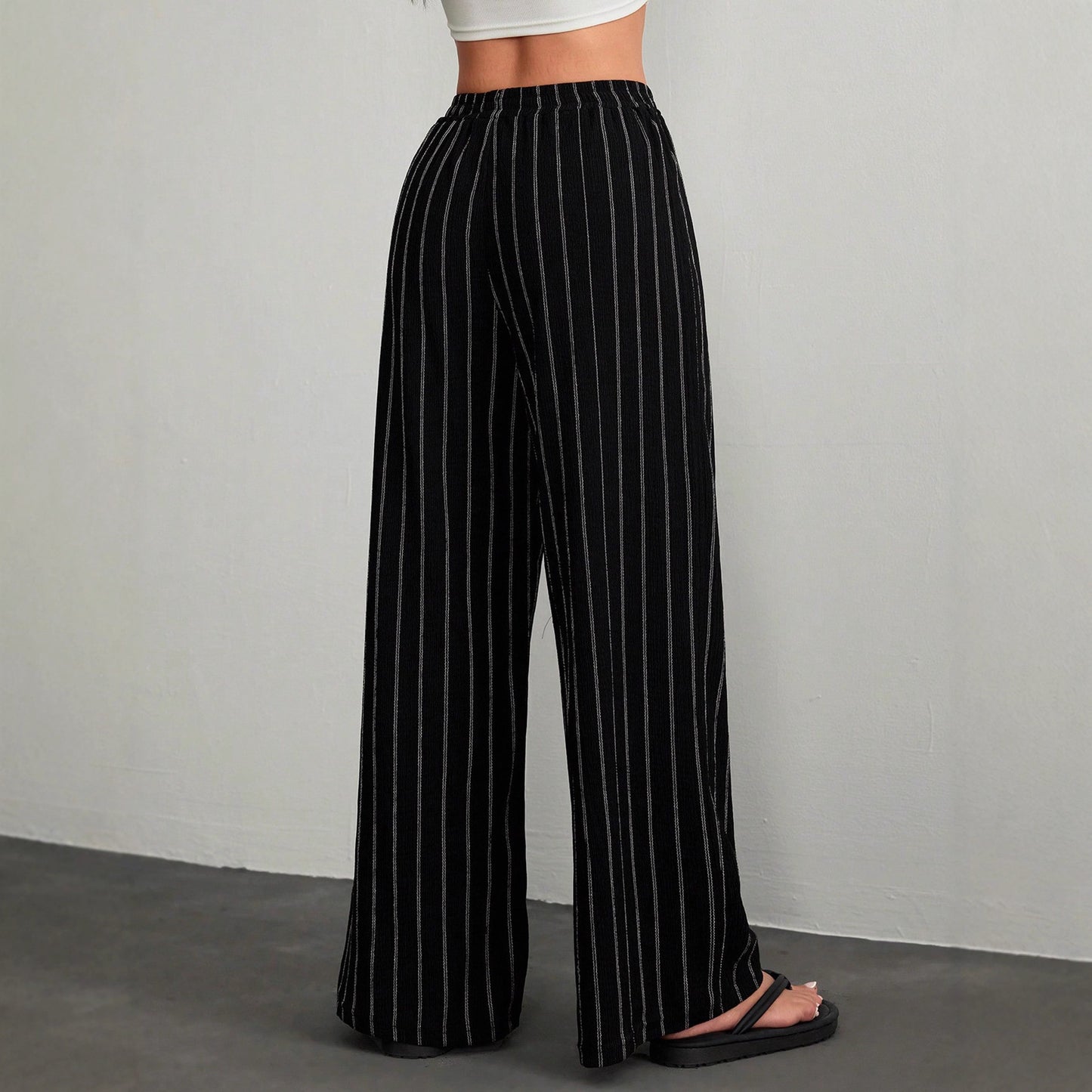 Black pinstripe pants worn by a person on a gray background