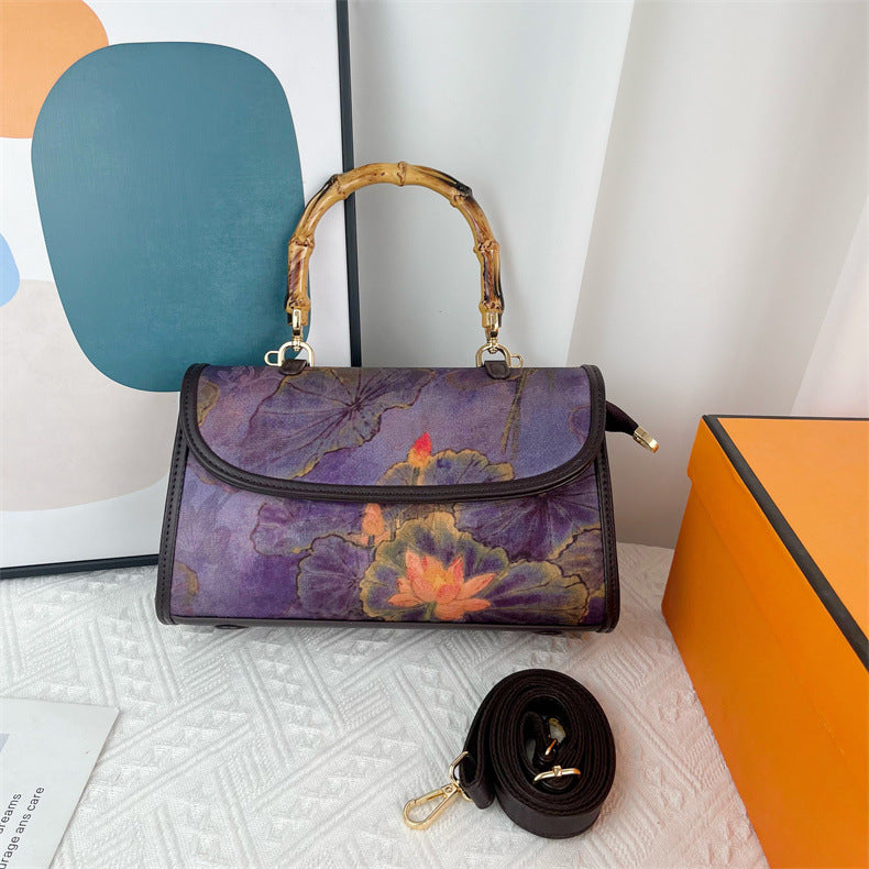 Floral-patterned handbag with a matching strap on a textured surface.
