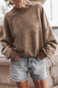 Person wearing a brown sweatshirt and denim shorts indoors