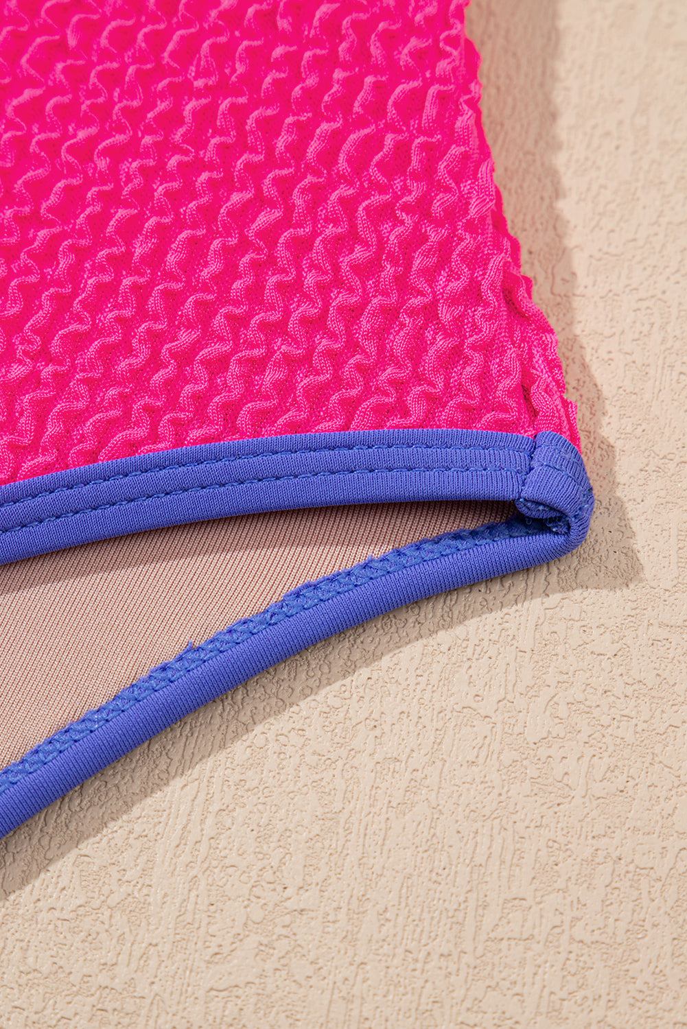 Close-up of a pink and blue fabric edge on a beige background