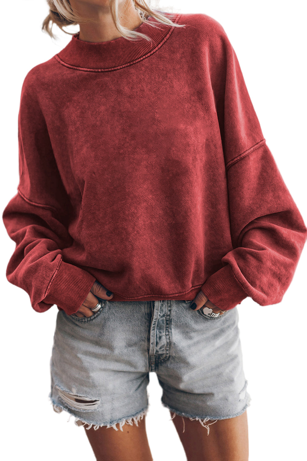 Person wearing a red sweatshirt and denim shorts on a white background