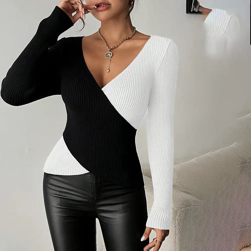 Person wearing a black and white ribbed sweater with leather pants against a neutral background