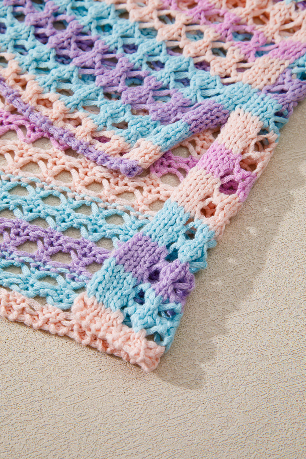 Crocheted blanket with pastel colors on a neutral surface