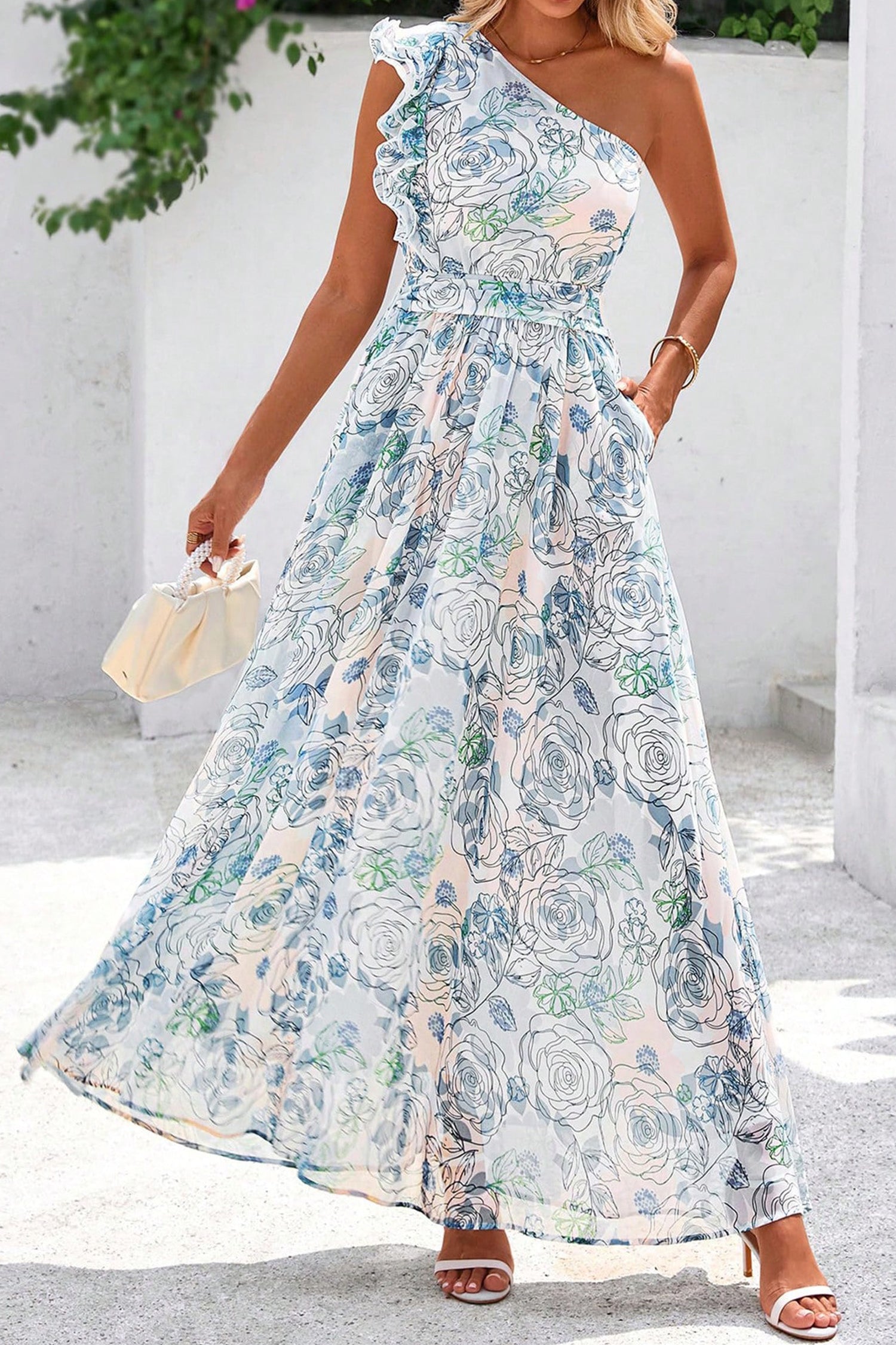 Woman wearing a floral one-shoulder dress against a white wall. Front view