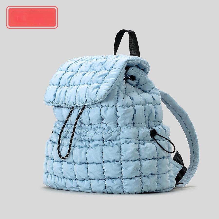 Light blue quilted backpack on a gray background